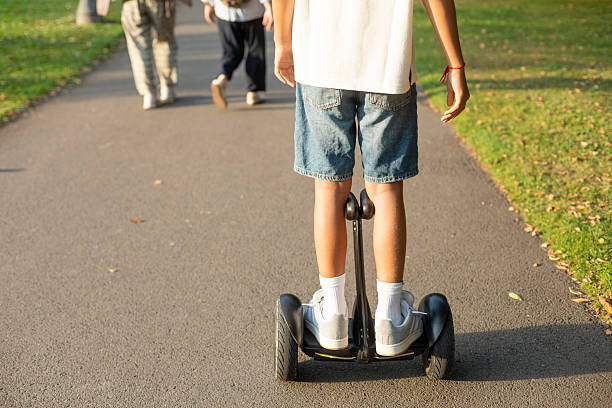 Modern urban mobility: boy using electric scooter in city park