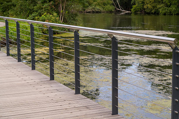 istock Modern wooden bridge with metal railing crossing a pond covered with algae 2228929716
