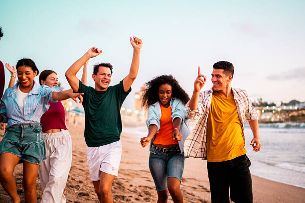 istock Young friends walking and dancing on the beach 2228930413