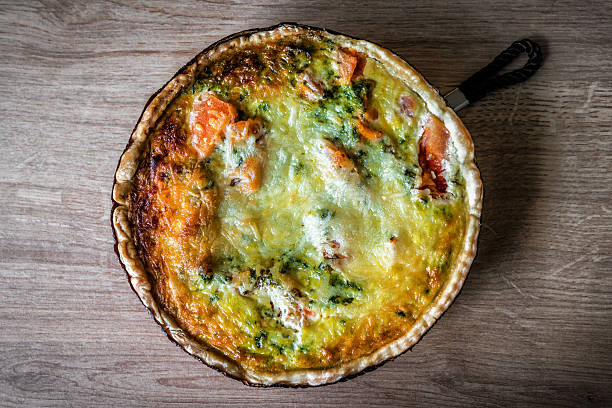 Delicious salmon quiche pie with broccoli and spinach on the kitchen table. Food and drink