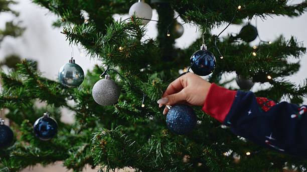 istock Woman Decorating Christmas Tree with Blue and Silver Balls 2228936877