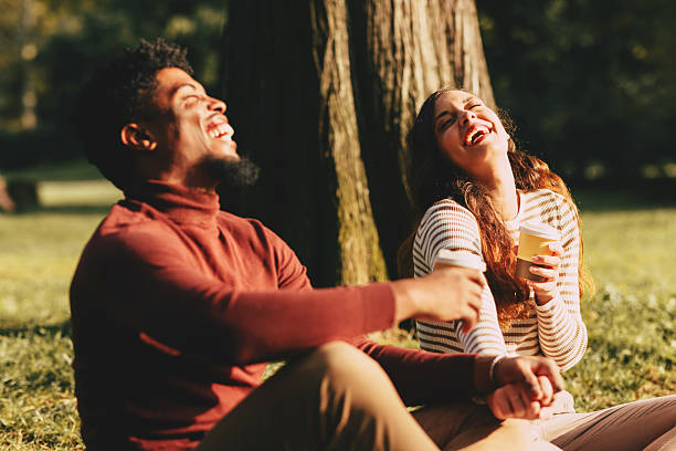 istock Happy couple laughing together while drinking coffee in park 2228940169