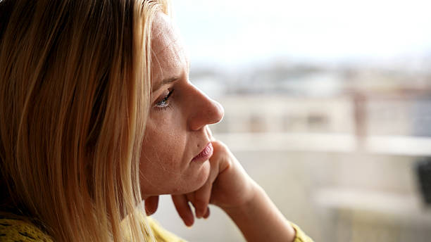istock Pensive Young Woman Looking Out the Window 2228942025