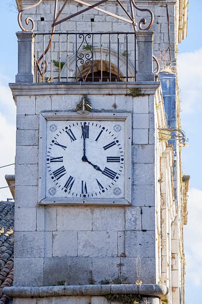 A close-up shot of an old clock with Roman numerals on a bell tower. The intricate details of the clock face and hands are clearly visible, showcasing a timeless and classic design.
