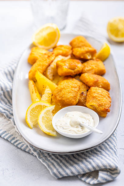 istock Traditional fish and chips with lemon and tartar sauce on serving plate 2228942859