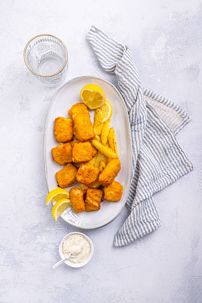 istock Traditional fish and chips with lemon and tartar sauce on serving plate 2228942940