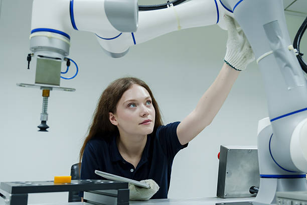 istock female automation trainee inspecting robotic system during training session in smart factory adjusting robotic arm using gloves and tablet to control precision robotic assembly process 2228944910