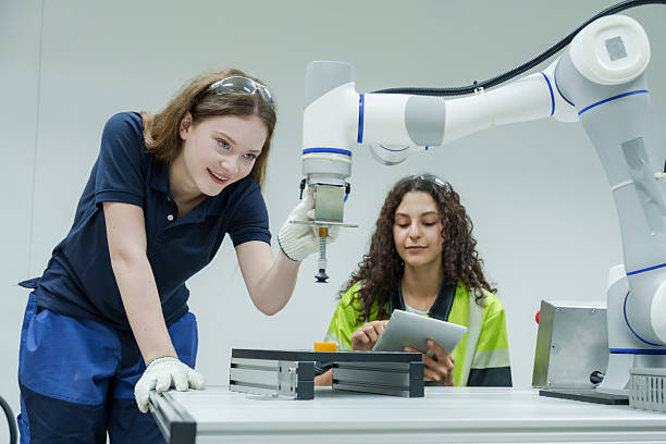 istock female automation trainee operating robotic arm with guidance from supervisor during robotics education session in smart factory teamwork learning with tablet based control system 2228944943