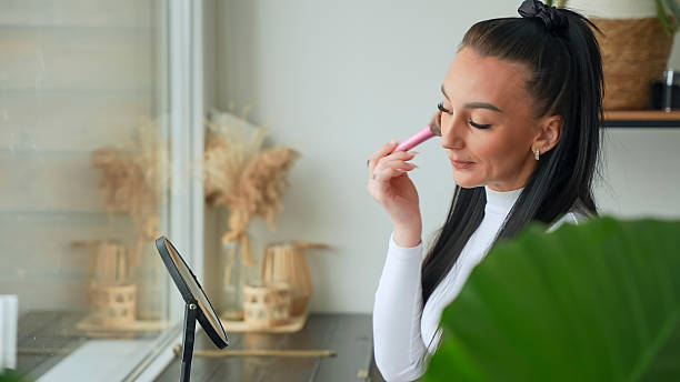 istock Woman Applying Makeup with Brush Looking in the Mirror 2228946941