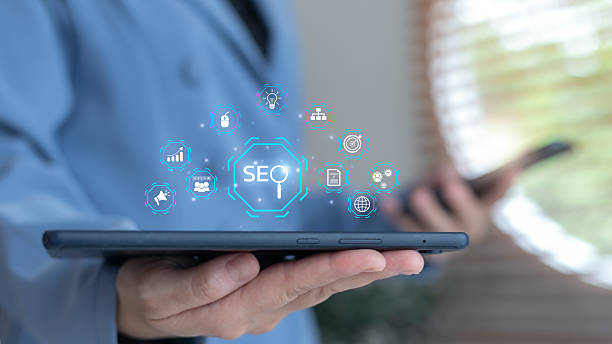 istock Hand holding a tablet with floating SEO ecosystem icons, including marketing, analytics, content, keyword, and target. Concept of search engine optimization, digital growth, and web ranking. 2228951352