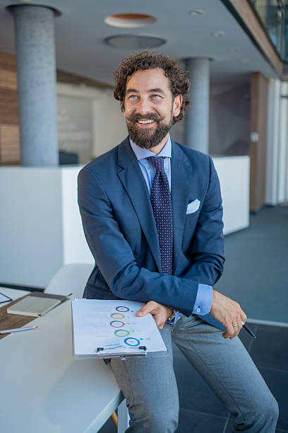 istock Smiling businessman holding charts in modern office 2228953035