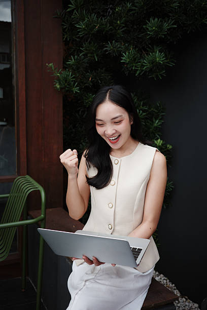 istock Young Asian businesswoman expressing excitement while working remotely on her laptop, celebrating a successful outcome 2228954334
