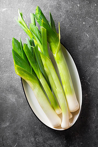 Bunch of fresh leeks on dark background vertical photo top view