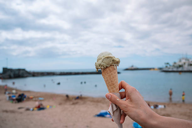istock A person holding a green ice cream cone on a beach. 2228957202