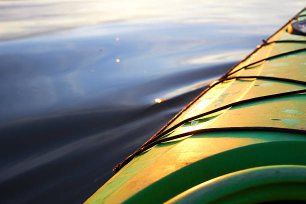 Fragment of a green kayak at water surface