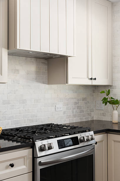 istock A kitchen stove and range hood detail with black countertop and tile backsplash. 2228961284
