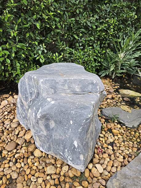 istock Natural Stone Rock on Pebble Bed Surrounded by Green Foliage 2228961387