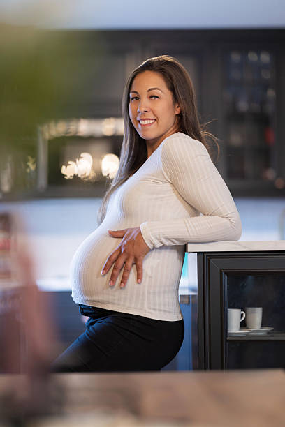 istock Pregnant woman joyfully smiling while leaning on a counter at home 2228962445