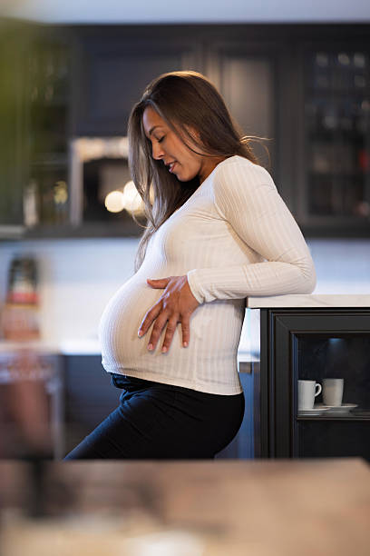 istock Pregnant woman reflecting thoughtfully while leaning on a counter in a kitchen 2228962453
