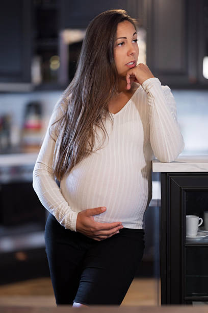 Pregnant woman pondering thoughtfully in a modern kitchen setting