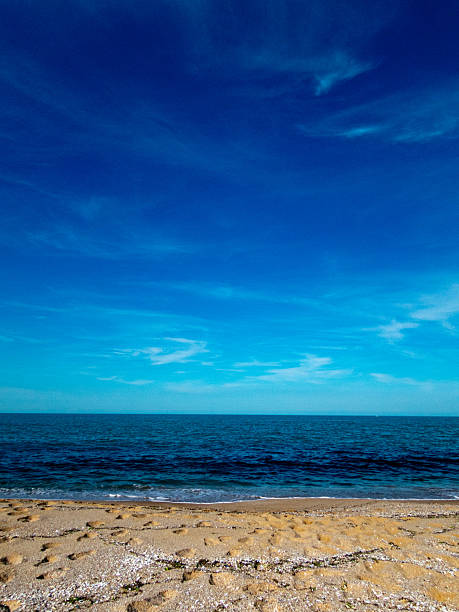 Seascape with beach, waves, sun and empty blue sky