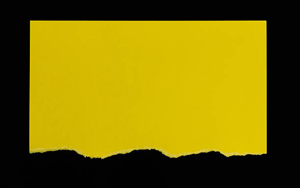 istock Half a piece of yellow paper on black background 2228963151