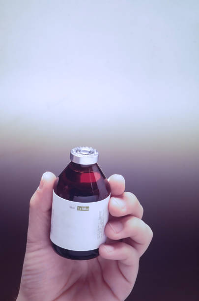 A hand holds an unlabeled medicine bottle.
