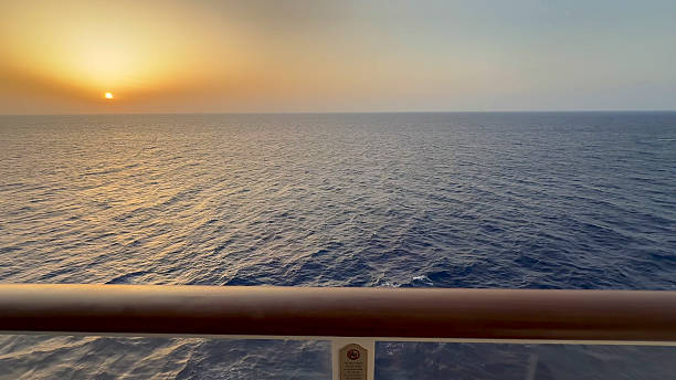 View past railing, on deck of ship, to sunrise over Caribbean Sea, Cozumel