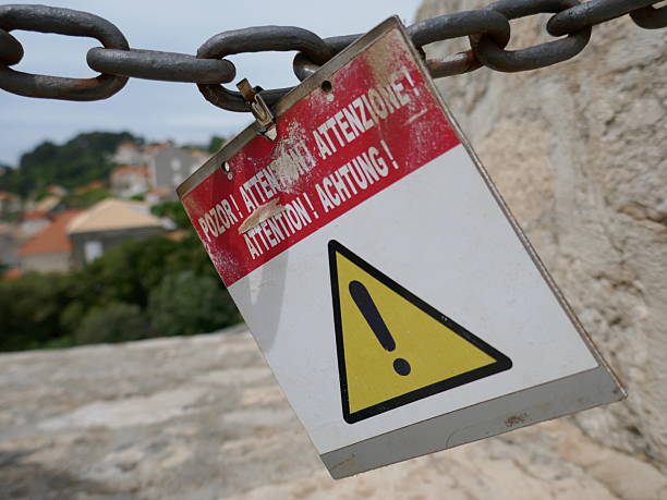 istock Danger attention sign in multiple languages hanging at travel destination 2228968190