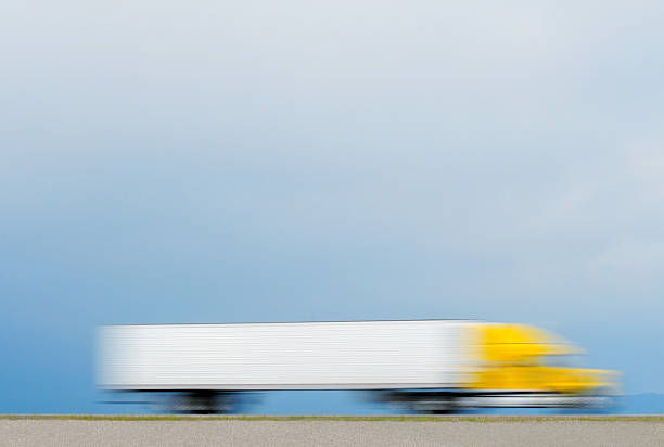 A blurred-motion photograph of a tractor trailer traveling on a highway.