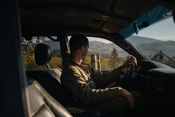 An Asian Chinese woman is sitting inside an old-fashioned SUV, smiling and looking away at the savanna near Bromo Volcano in East Java, Indonesia during sunset.
