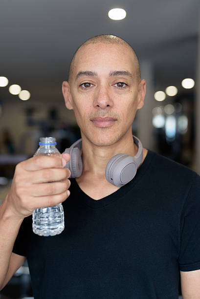 istock Hispanic bald man athlete in gym drinking water from bottle 2228975400