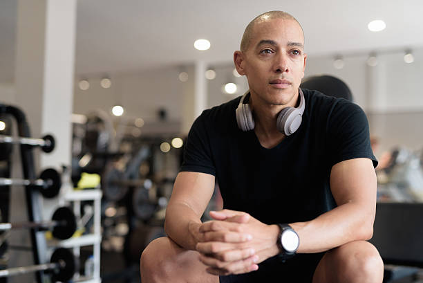 Hispanic bald man athlete in gym sitting ready for workout