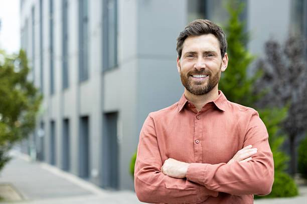 istock A handsome man with a beard confidently smiles outdoors in front of an office building. 2228979937