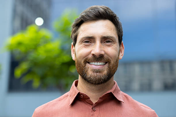 istock A smiling man with a beard, looking happy and confident outdoors. 2228979944
