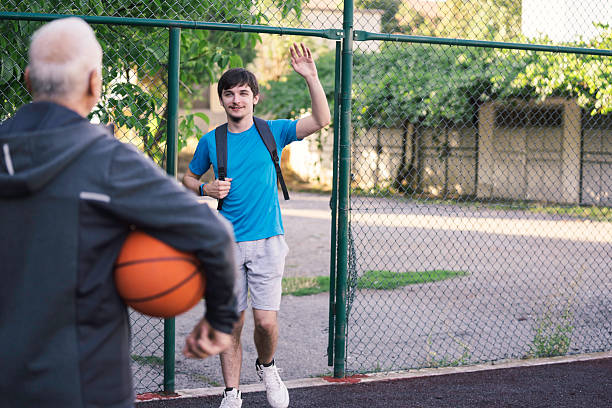 An older man holds a basketball as he walks beside a younger man, illustrating the connection formed through sports and the importance of mentorship in building relationships.