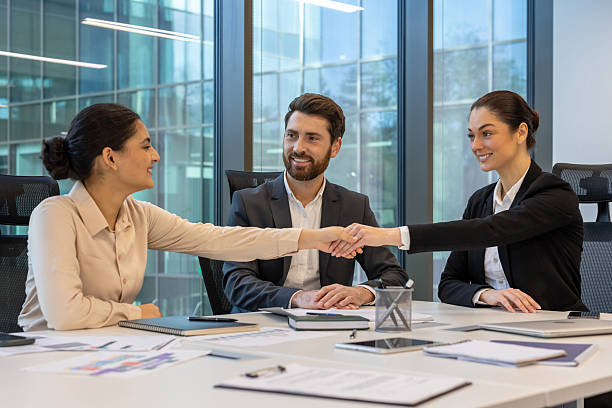 istock Business professionals in a modern office handshake agreement indicating teamwork and successful collaboration around conference table 2228981539