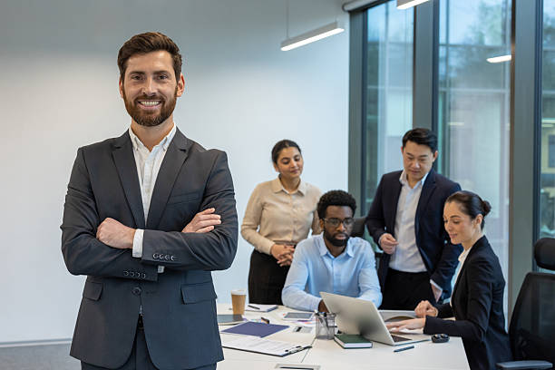 istock Confident businessman standing in modern office with diverse team engaged in collaborative meeting 2228981551