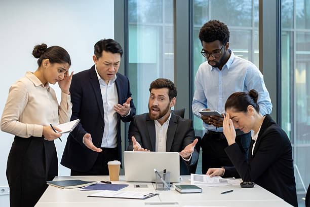 istock A diverse group of colleagues express frustration around a table with a laptop, showing disappointment with project outcomes and facing challenges. 2228981593