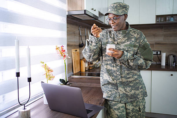 istock Soldier eating yogurt and looking at laptop in kitchen 2228981895