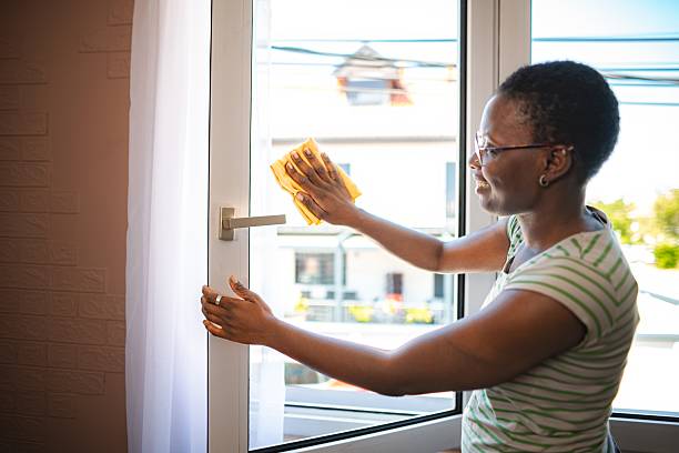 istock Smiling housekeeper cleaning a window with a yellow cloth 2228982010