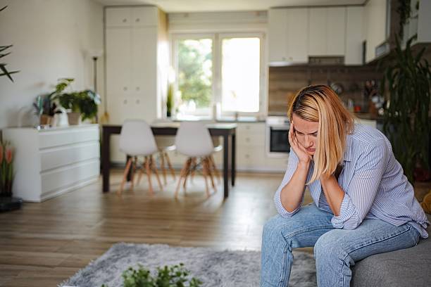 istock Sad woman sitting on sofa at home, having mental health problems 2228982257