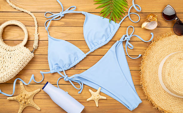 istock Blue bikini with beach accessories on wooden background, top view 2228988528