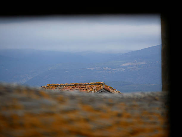 view through a window on a historical roof top and distant mountains