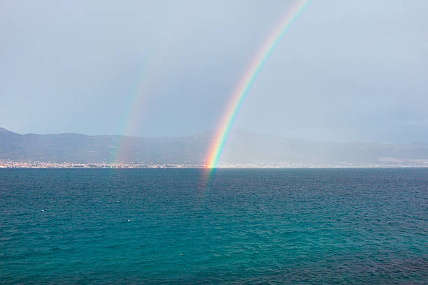 istock Vivid double rainbow arcs over a tranquil sea 2228992862
