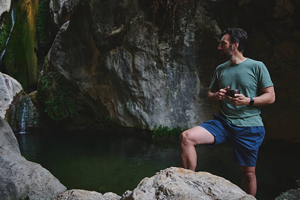 istock Man Relaxing Near a Scenic Rocky Waterfall in a Tranquil Forest 2228993266