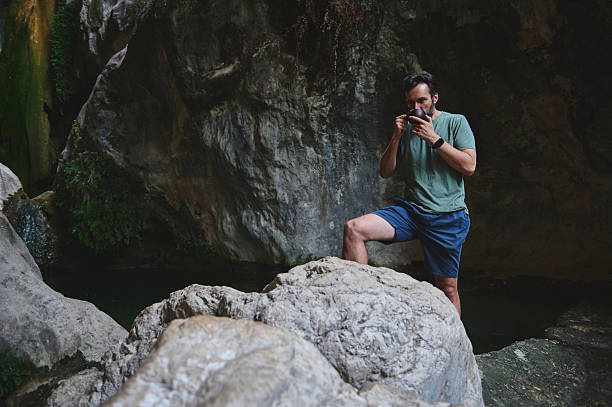 istock Man Enjoying a Refreshing Moment Near a Rocky Waterfall Scene 2228993411