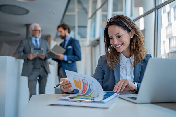 istock Businesswoman smiling while analyzing charts in modern office 2228993615