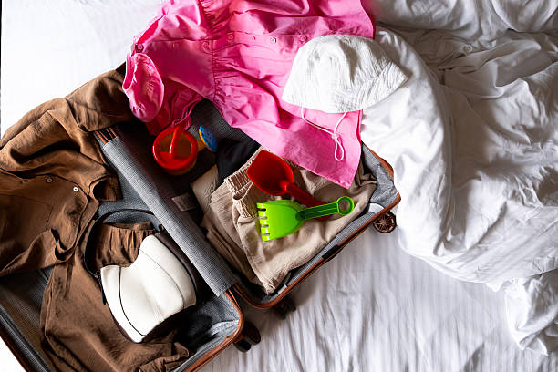 istock Open suitcase with summer clothes and beach toys on a hotel bed 2229005007