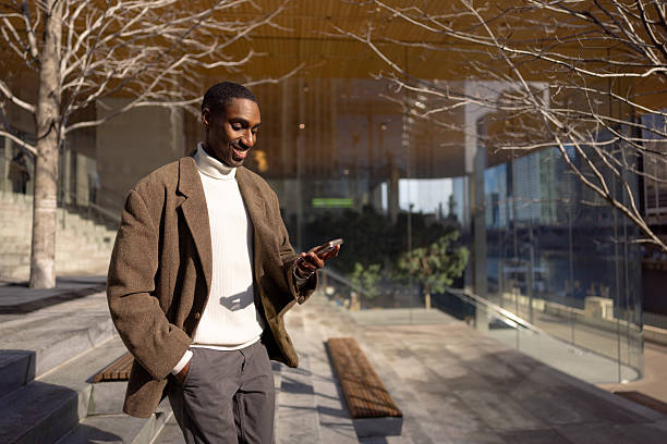 istock Stylish businessman using smartphone in urban setting, enjoying sunny day 2229010481